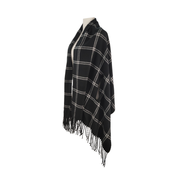 Black and white plaid poncho with fringe on a mannequin against a white background